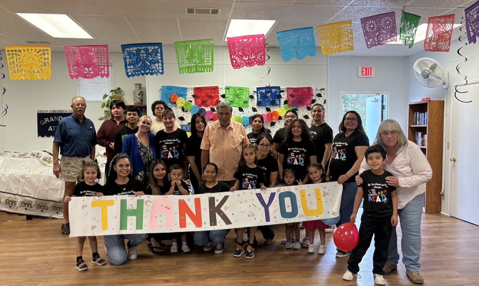 Families and volunteers gathered behind a hand-lettered THANK YOU banner at a BASIC celebration