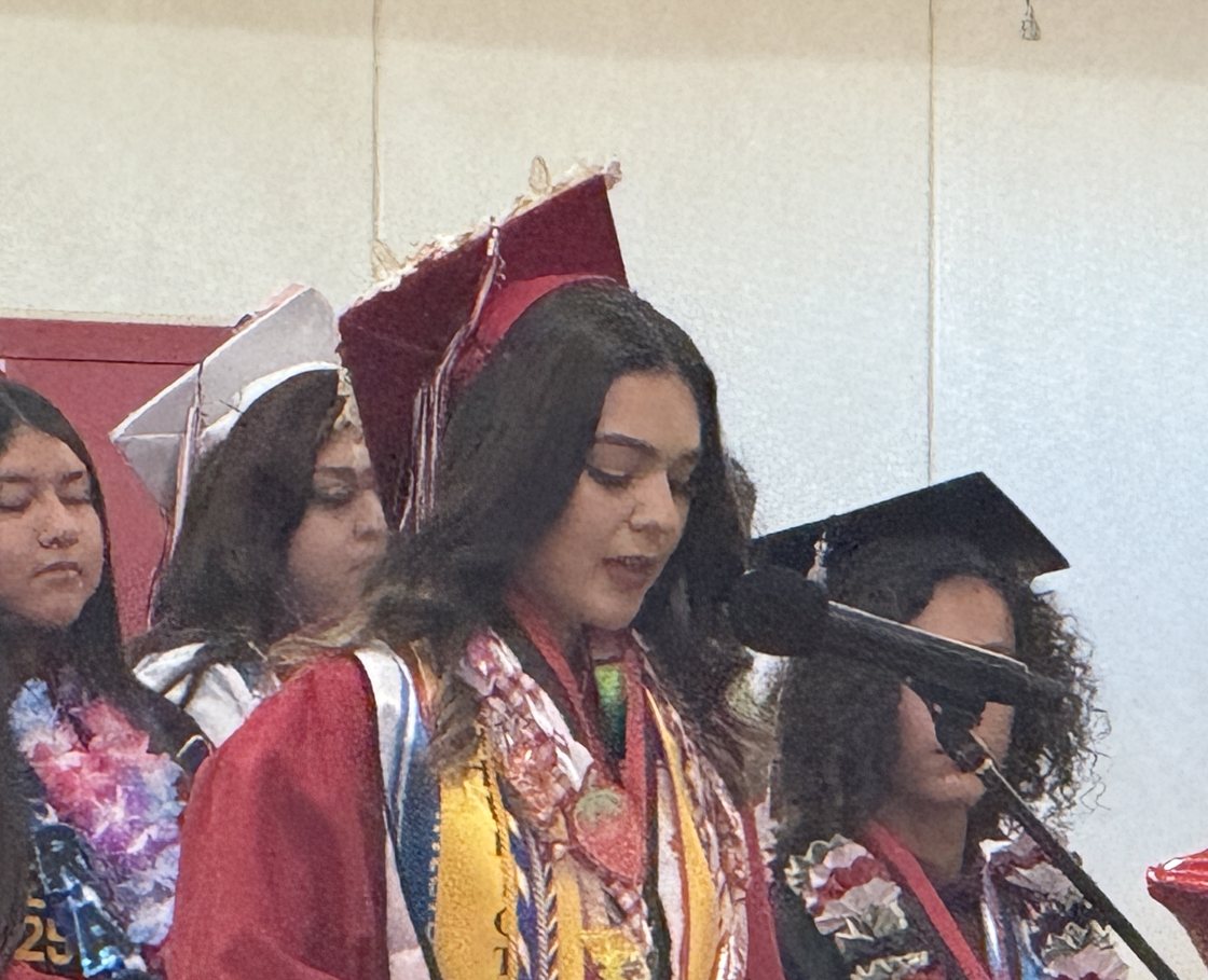A Borrego Springs High School graduate speaking at commencement, her classmates seated behind her