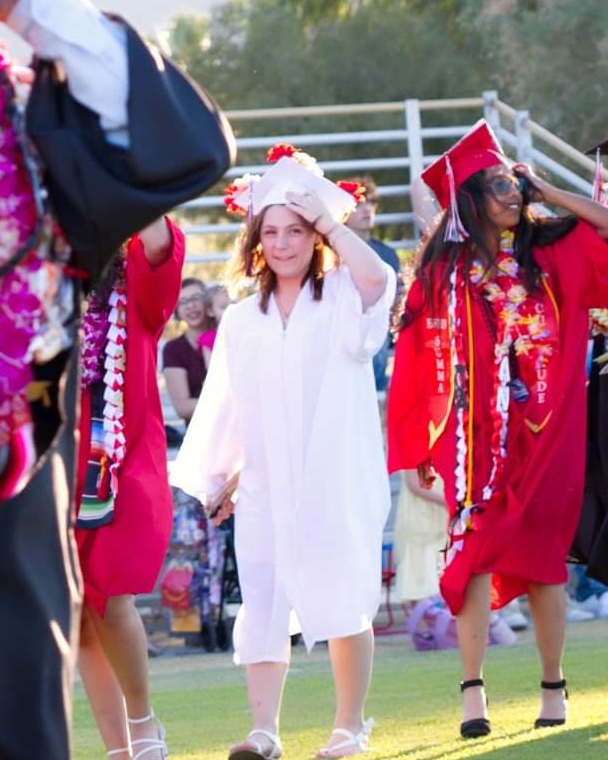 A Borrego Springs High School graduate in a white cap and gown at the commencement ceremony