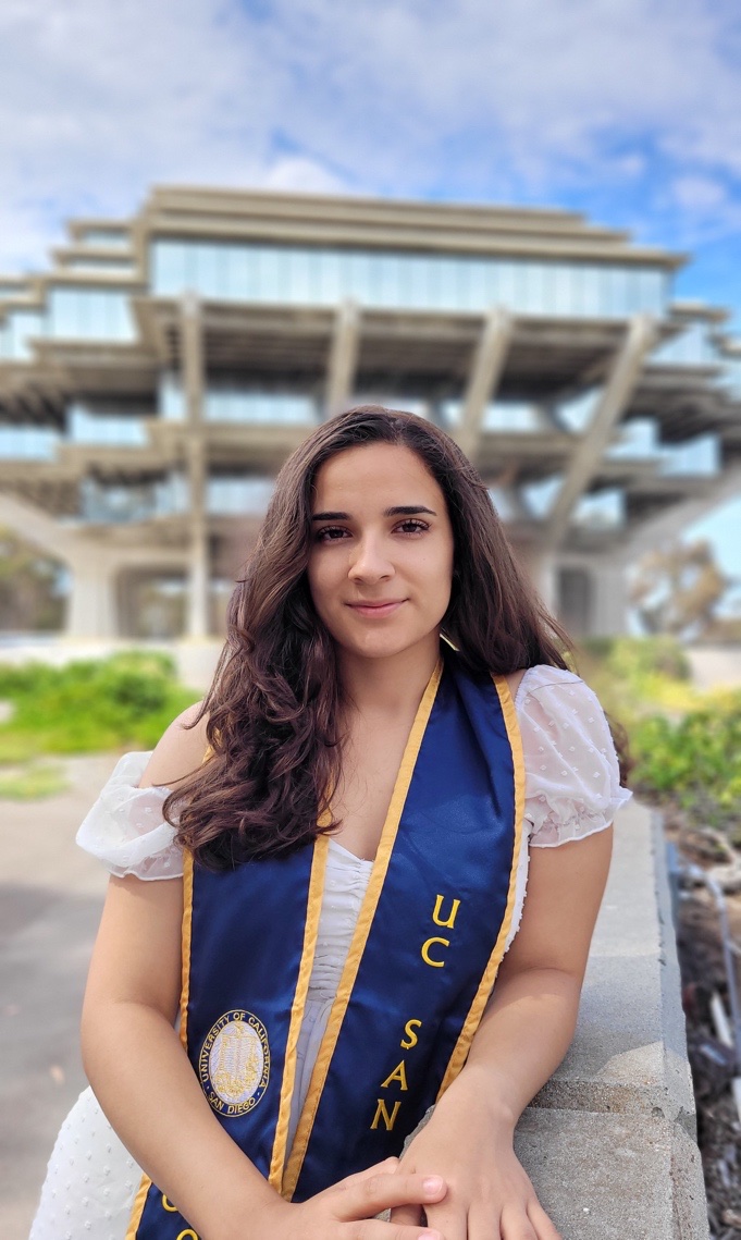 Karen Garcia in her UC San Diego graduation stole, standing in front of the Geisel Library