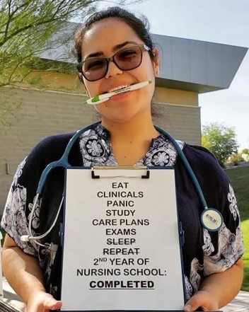 A BASIC scholar holding a sign reading second year of nursing school completed