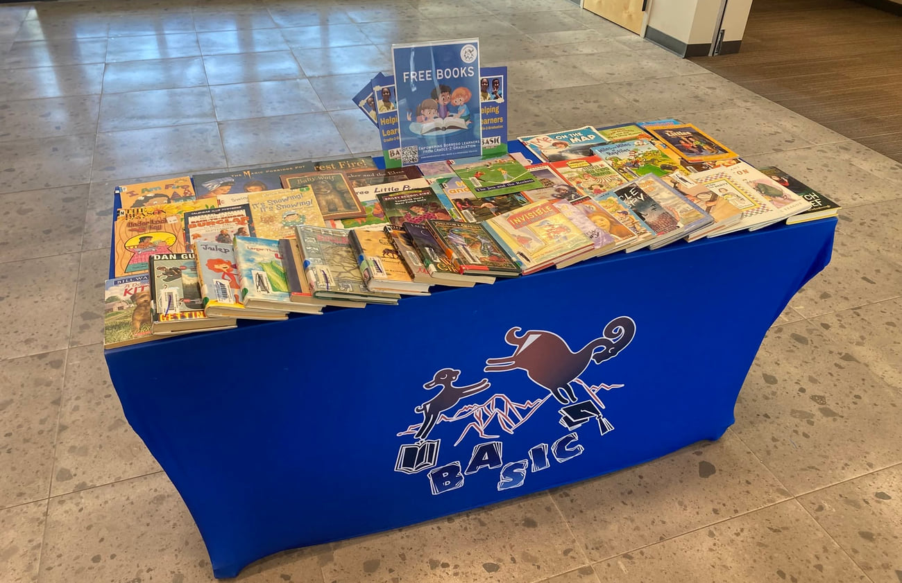 A BASIC free-books table stocked with children’s books in a community building lobby