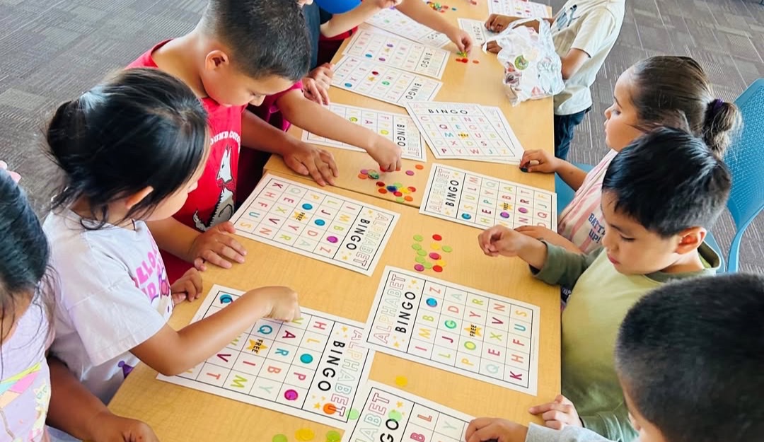 Students playing an alphabet bingo game at a BASIC Learning Academy table